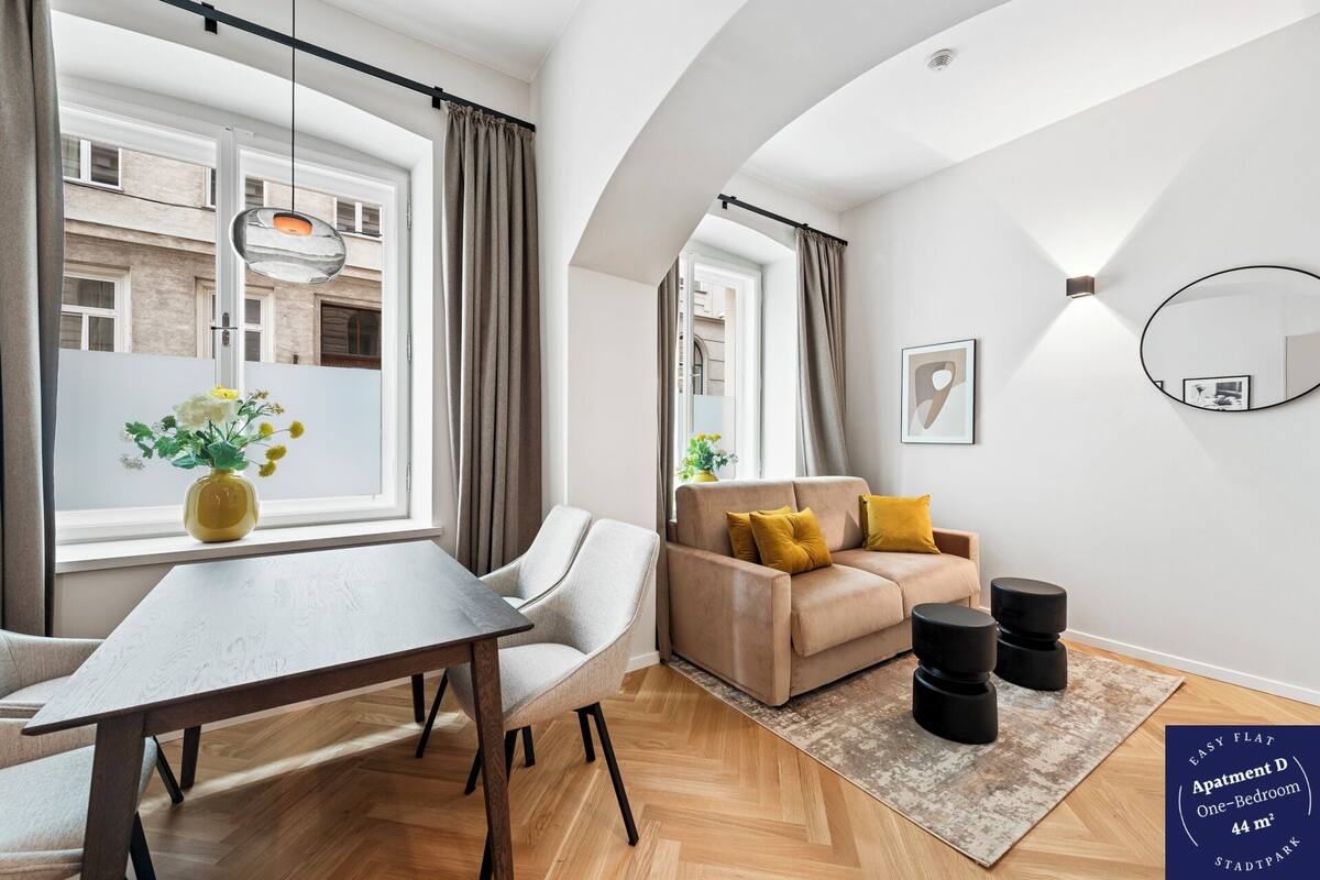 A modern living room with a sofa, a dining table, and a large window.
