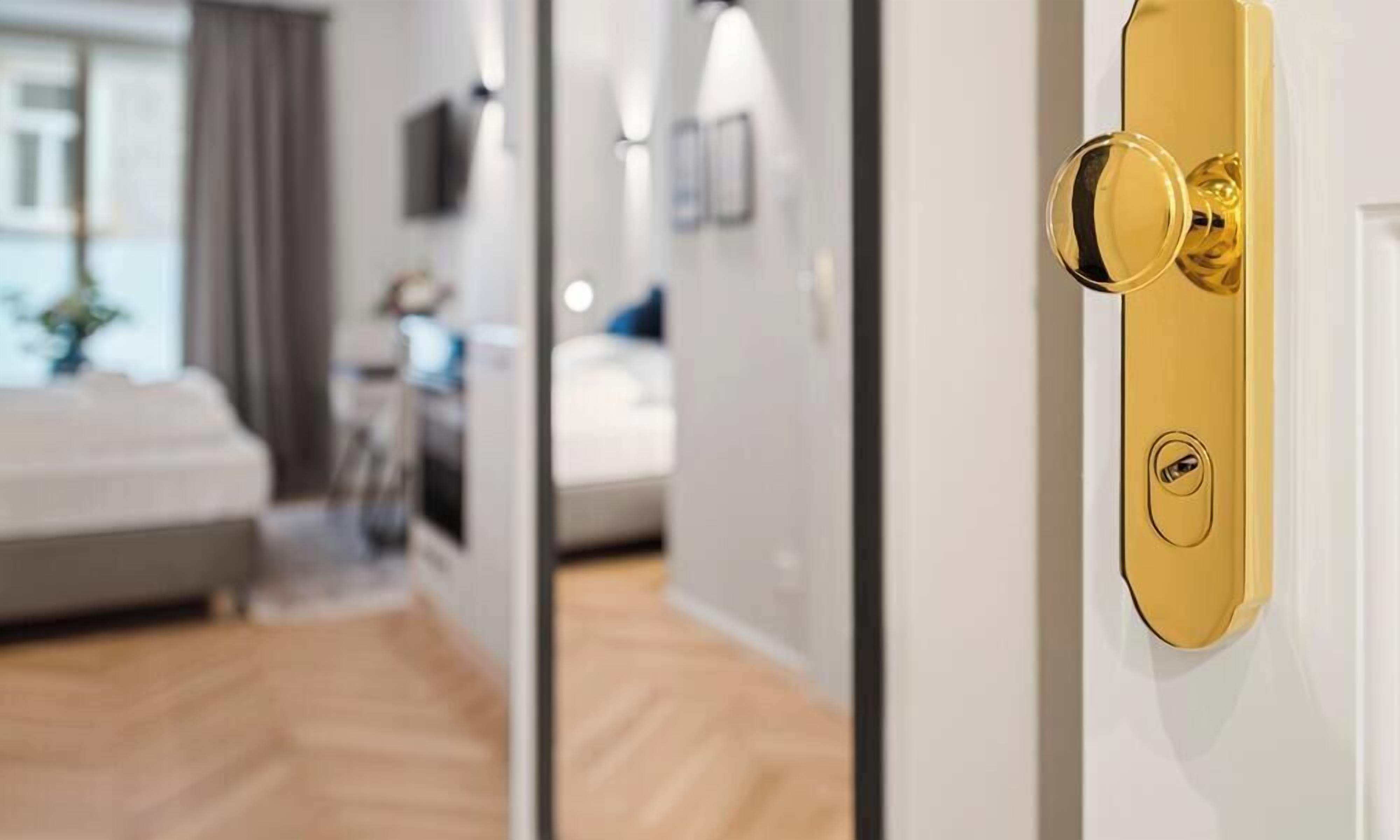 A hotel room with a modern design, featuring a white door with a gold handle and a sign indicating 'Easy Flat Apartment C Studio 20 m² Stadtpark'.