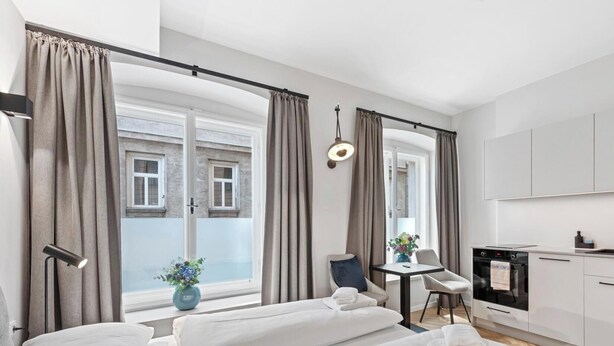 Een moderne slaapkamer met een groot bed, een klein bureau en een kitchenette.