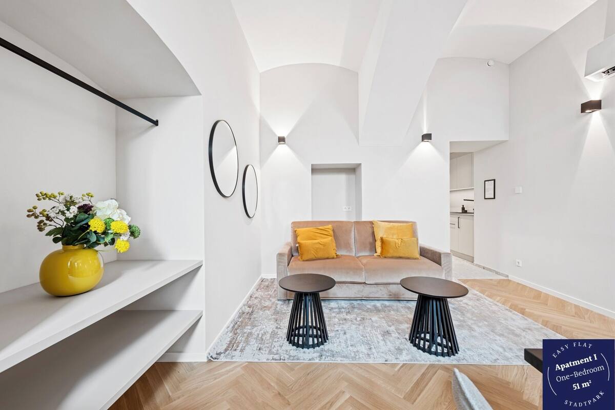 A modern apartment with a sofa set, two side tables, and a yellow vase with flowers.