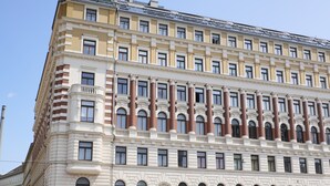 Een meerlaags hotel met een klassieke architectuur, met een symmetrische gevel, grote ramen en een opvallend hoektorentje.