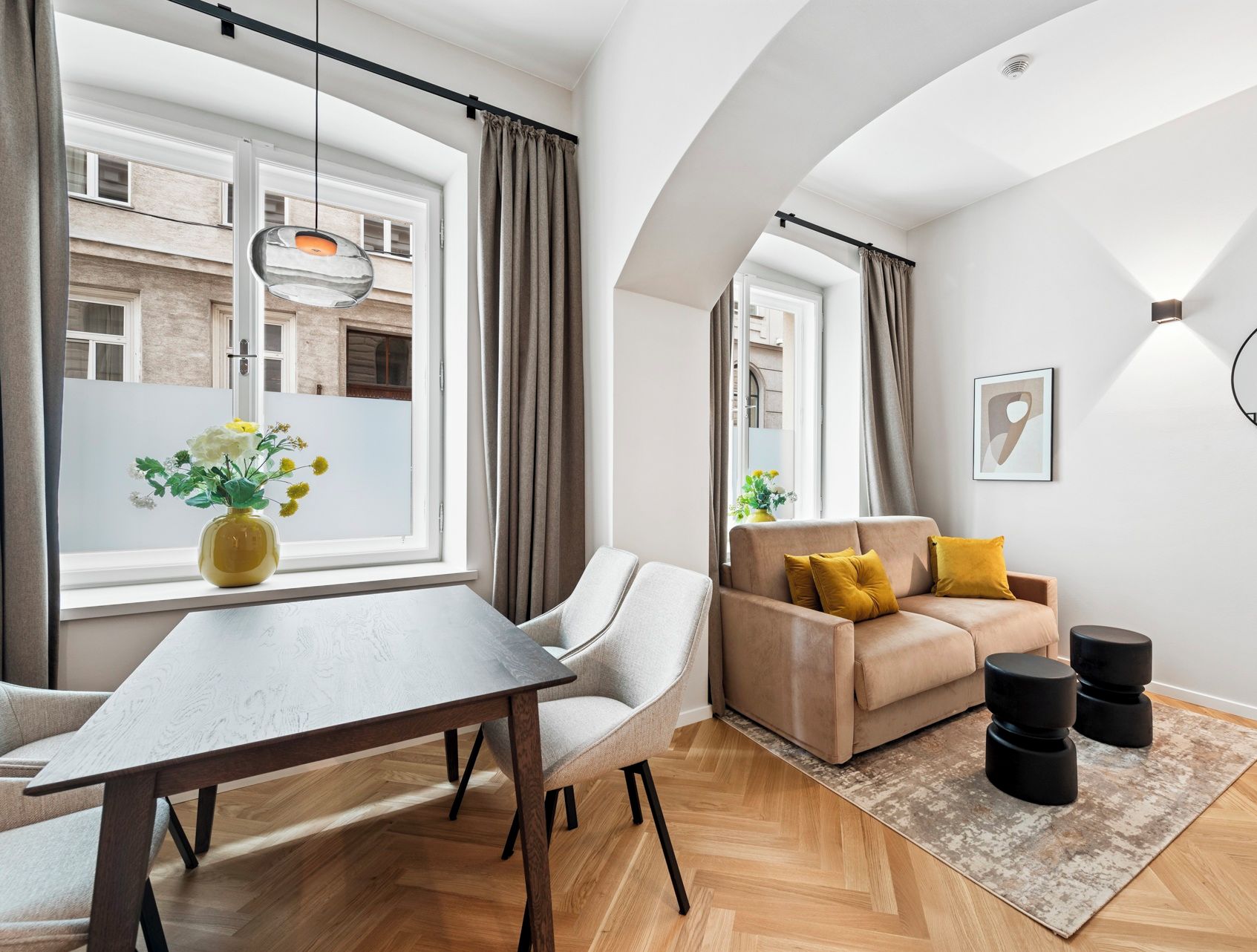 Een moderne woonkamer met een bank, een eettafel en een groot raam.