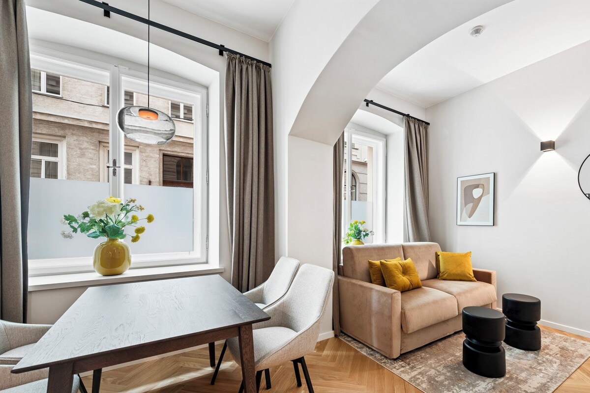 A modern living room with a sofa, a dining table, and a large window.