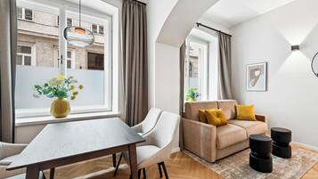 Een moderne woonkamer met een bank, een eettafel en een groot raam.