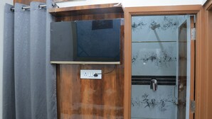 Un baño con tocador de madera, ducha con puertas de vidrio y cortina gris.