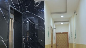 Un pasillo con una pared de mármol, suelo de madera y una puerta al final.