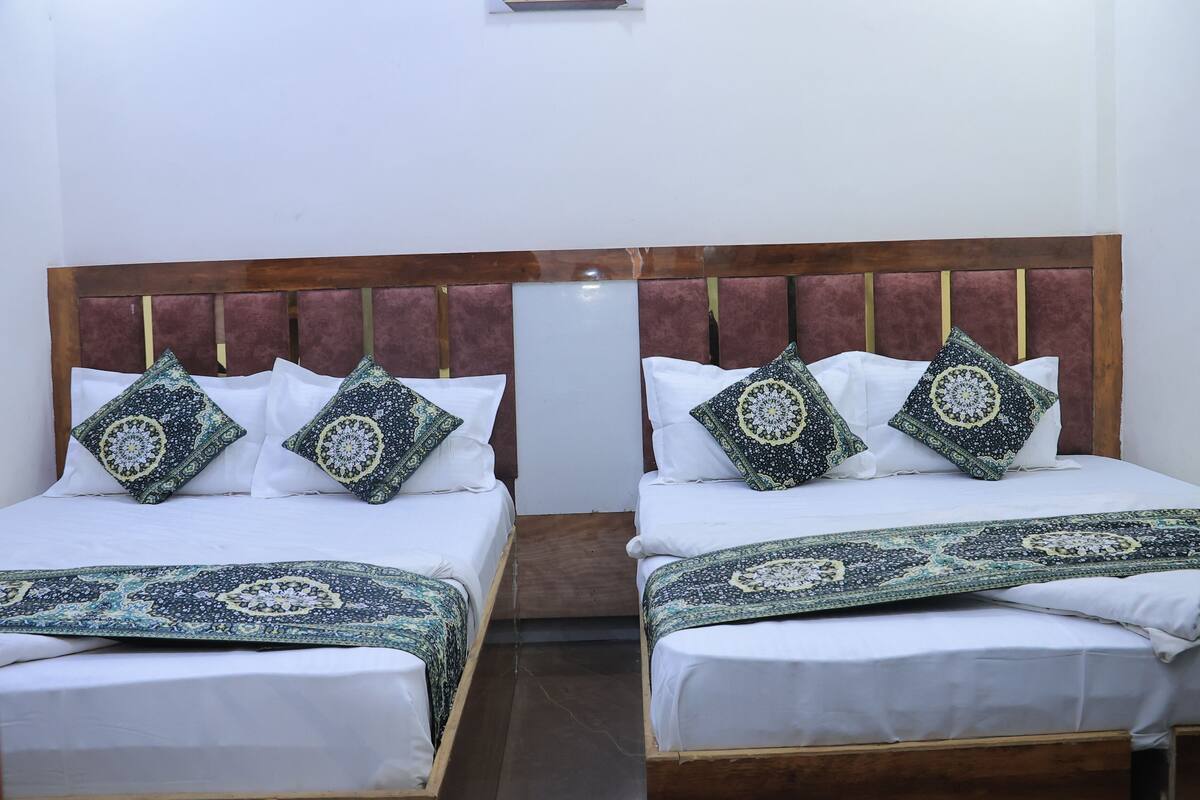 A double bed with a wooden headboard, two pillows with a geometric pattern, and a matching bed runner.