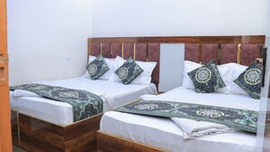 Dos camas dobles con cabeceros de madera y cabeceros a juego, cada una con almohadas estampadas y una manta decorativa.