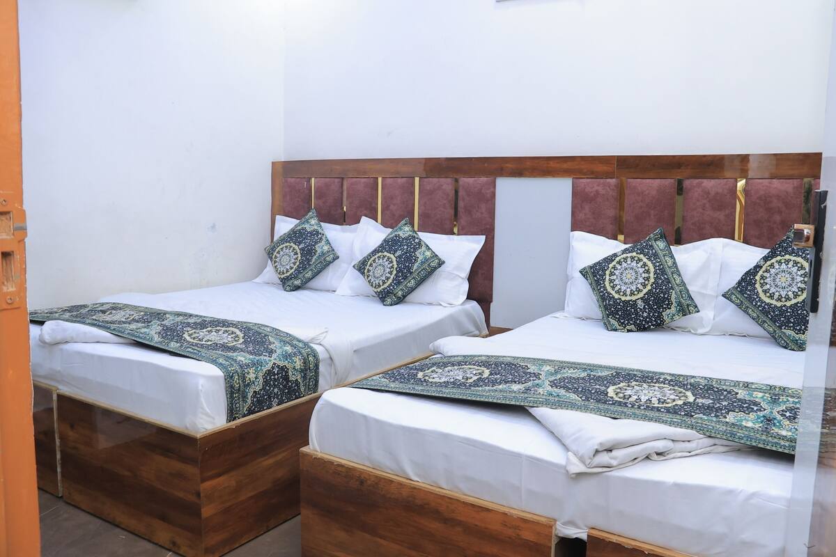 Two double beds with wooden headboards and matching headboards, each with patterned pillows and a matching throw blanket.