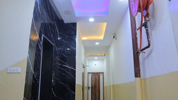 Un pasillo con pared de mármol negro, una puerta de madera, e iluminación empotrada con una luz de acento morada.
