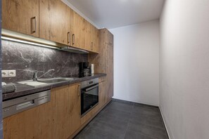 A modern kitchen with wooden cabinets, a built-in oven, and a stainless steel sink.