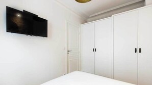 A bedroom with a bed, a white wardrobe, and a mounted television. - Spacious Apartment 2BR/5P – Nogent-sur-Marne (Nogent-sur-Marne)