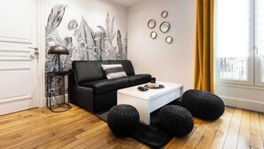 A modern living room with a black sofa, white coffee table, and black poufs. - Spacious Apartment 2BR/5P – Nogent-sur-Marne (Nogent-sur-Marne)