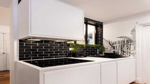 A kitchen with white cabinets, black backsplash, and a black stove. - Spacious Apartment 2BR/5P – Nogent-sur-Marne (Nogent-sur-Marne)