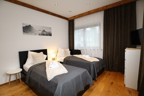 Una camera d'albergo con due letti, un tavolino, una TV e un quadro appeso al muro.