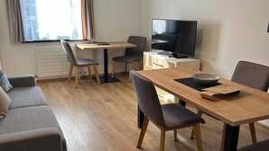 Ein modernes Wohnzimmer mit einer Couch, einem Esstisch mit Stühlen, einem Fernseher und einer Heizung.