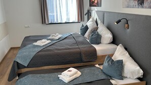 Ein Hotelzimmer mit Bett, Kissen, einer Nachttischlampe und einem Fenster mit Vorhängen.