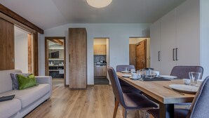 Un salon moderne avec un canapé, une table à manger dressée pour quatre personnes et une cuisine en arrière-plan.