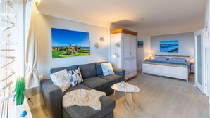 A modern living room with a sofa, a small round table, a bed, and a wardrobe. - Berolina 314 - Sea whispers - "Sea whispers" with a view of the infinite (Dahme)