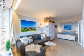 A modern living room with a sofa, a small round table, a bed, and a wardrobe. - Berolina 314 - Sea whispers - "Sea whispers" with a view of the infinite (Dahme)