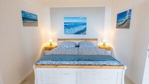 A bed with a patterned bedspread, two bedside lamps, and a large framed picture above the bed. - Berolina 314 - Sea whispers - "Sea whispers" with a view of the infinite (Dahme)