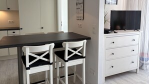 A modern kitchen with white cabinets, a black countertop, and two white chairs with black cushions. - Berolina 313 - More sea - "More sea" in view... exclusive vacation apartment in the (Dahme)
