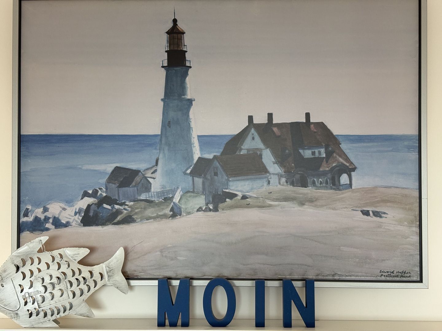 Une scène côtière avec un phare et des maisons, portant l’inscription « MOIN ».