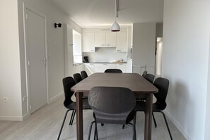 A modern kitchen with white cabinets, a wooden dining table, and black chairs.