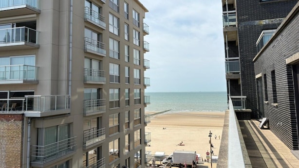 Un immeuble de grande hauteur doté de nombreux balcons donnant sur une plage.