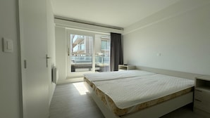 Une chambre moderne avec un grand lit, une petite table de chevet et une vue sur un balcon.