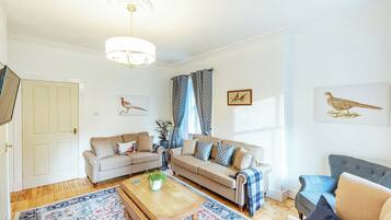 A living room with two sofas, a coffee table, a patterned rug, and wall art of birds.