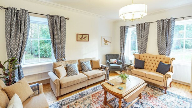 A spacious living room with two sofas, a coffee table, and a chandelier.