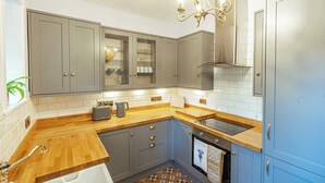 A modern kitchen with grey cabinets, a wooden countertop, a built-in oven, and a stainless steel sink.