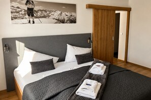 A neatly made bed with a gray quilt, white pillows, and a folded towel.