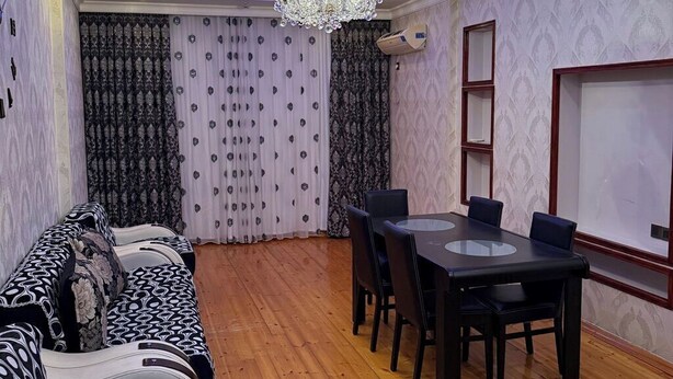 A dining area with a chandelier, a wooden floor, and patterned curtains. - Sabir bir (Baku)