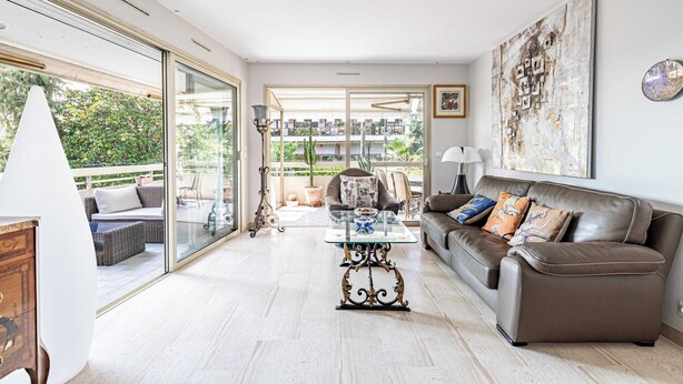 A spacious living room with a glass door leading to an outdoor area, a brown leather sofa, and a glass coffee table. - Apt with A/C and balcony - 1bdr/4P - Cannes/ beach (Cannes)