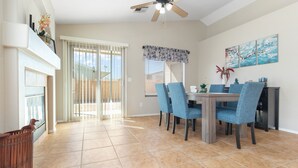 Comedor con mesa, sillas, ventilador de techo y vistas al exterior.