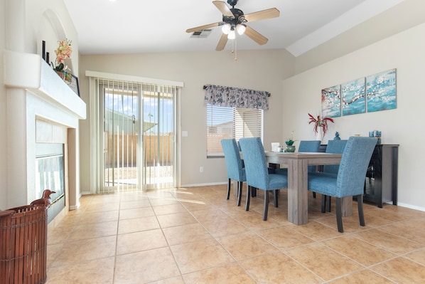 A dining area with a table and chairs, a ceiling fan, and a view to the outside.