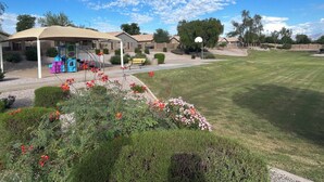 Zona residencial con un área de juegos techada, cancha de baloncesto y césped cuidado.