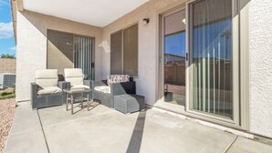 Un patio cubierto con mobiliario de mimbre y puertas correderas de vidrio.