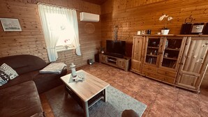 Habitación con paneles de madera, sofá, televisor, mueble de madera y una pequeña mesa con adornos.