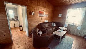 Una habitación acogedora con detalles de madera, un sofá, una mesita y una ventana con cortinas.