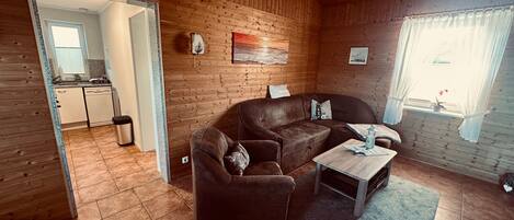 Una habitación acogedora con detalles de madera, un sofá, una mesita y una ventana con cortinas.