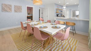 A modern dining area with a white table, pink chairs, and a yellow striped rug. - Bradenton Bliss | Heated Pool | Hot Tub | Tiki Bar (Bradenton)