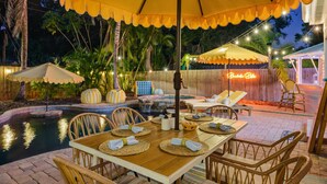 An outdoor dining area with a pool, umbrellas, and lounge chairs. - Bradenton Bliss | Heated Pool | Hot Tub | Tiki Bar (Bradenton)