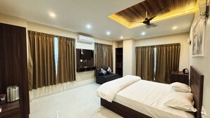 A modern bedroom with a large bed, dark wood furniture, and a ceiling fan. - The Kari INN (Udaipur)