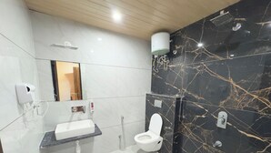 A modern bathroom with a marble vanity, a toilet, a shower, and a hand dryer. - The Kari INN (Udaipur)