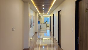 A hallway with a wooden ceiling, recessed lighting, and a checkered floor. - The Kari INN (Udaipur)