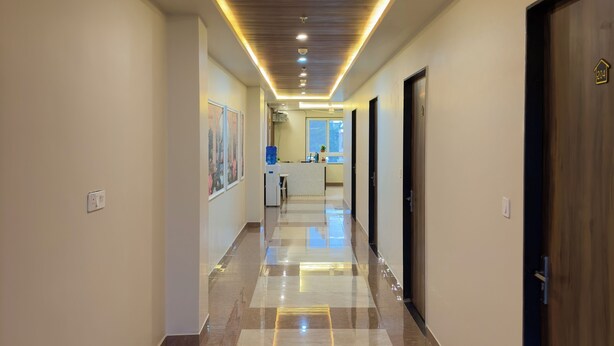 A hallway with a wooden ceiling, recessed lighting, and a checkered floor. - The Kari INN (Udaipur)