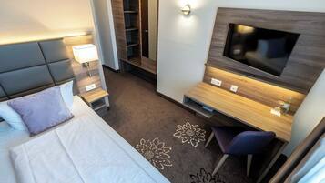 A hotel room with a bed, a desk, a TV, a wardrobe, and a bathroom.